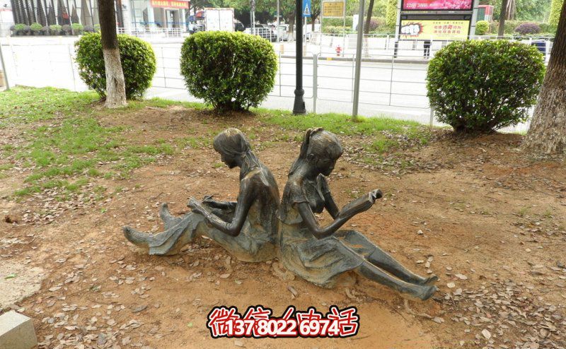 公园草坪女孩背对背的读书雕塑